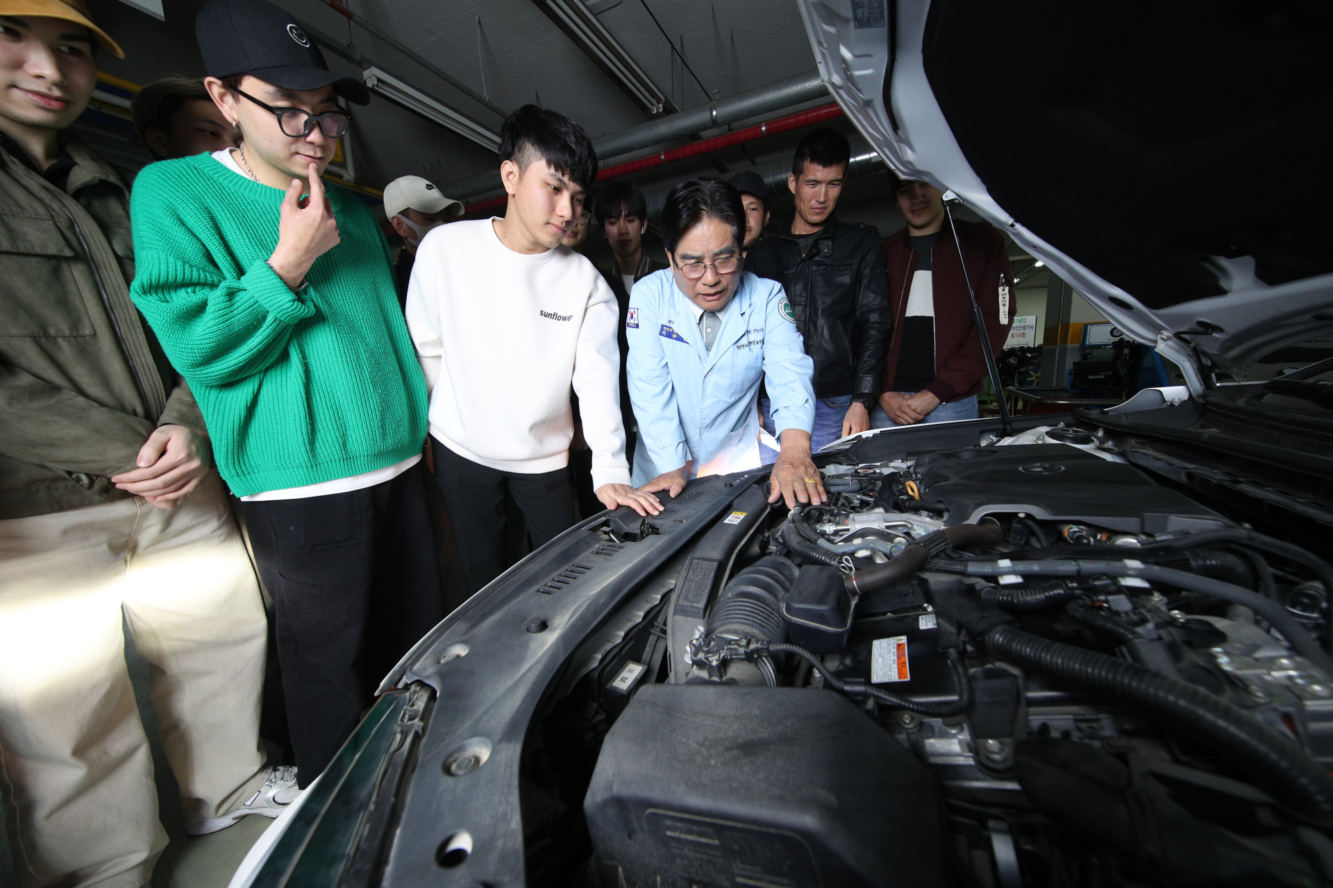 자동차 내부를 들여다보며 설명해주는 교수님과 집중하는 학생들