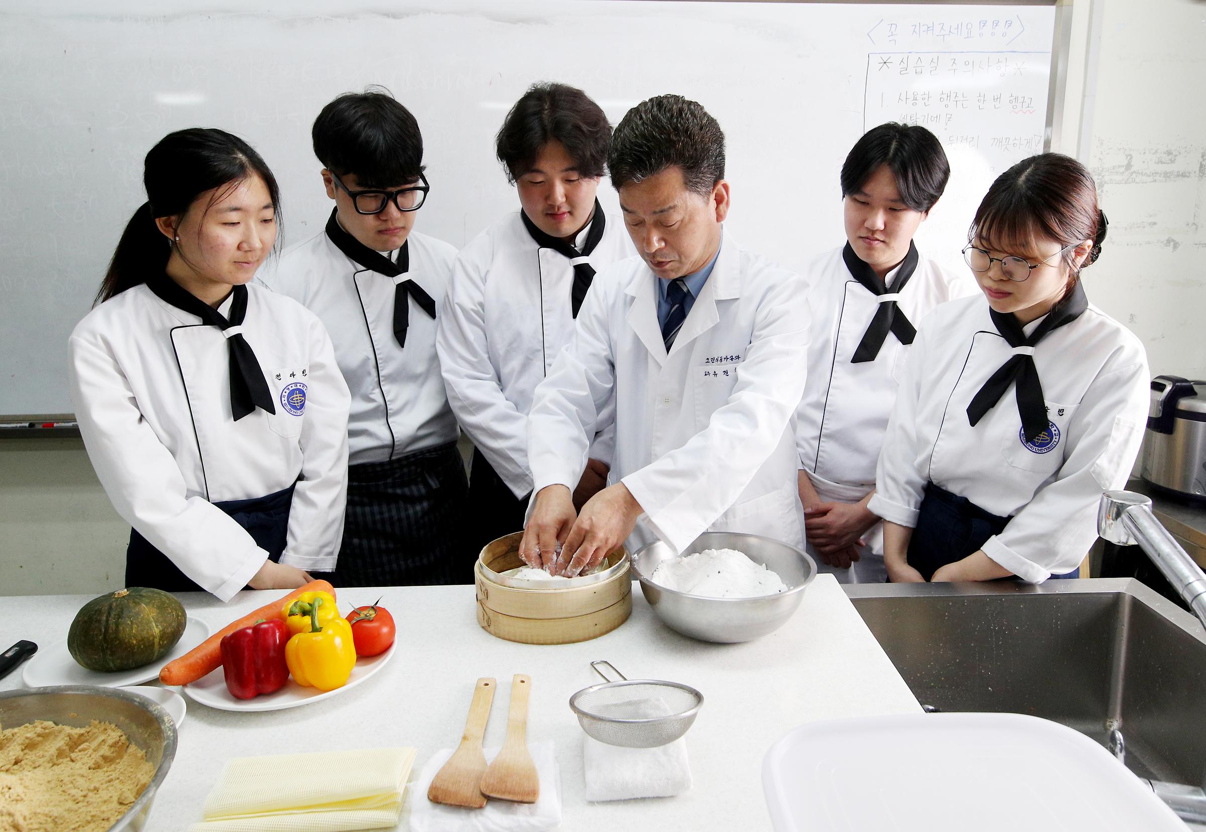 채소를 손질하는 교수님과 지켜보는 학생들의 사진