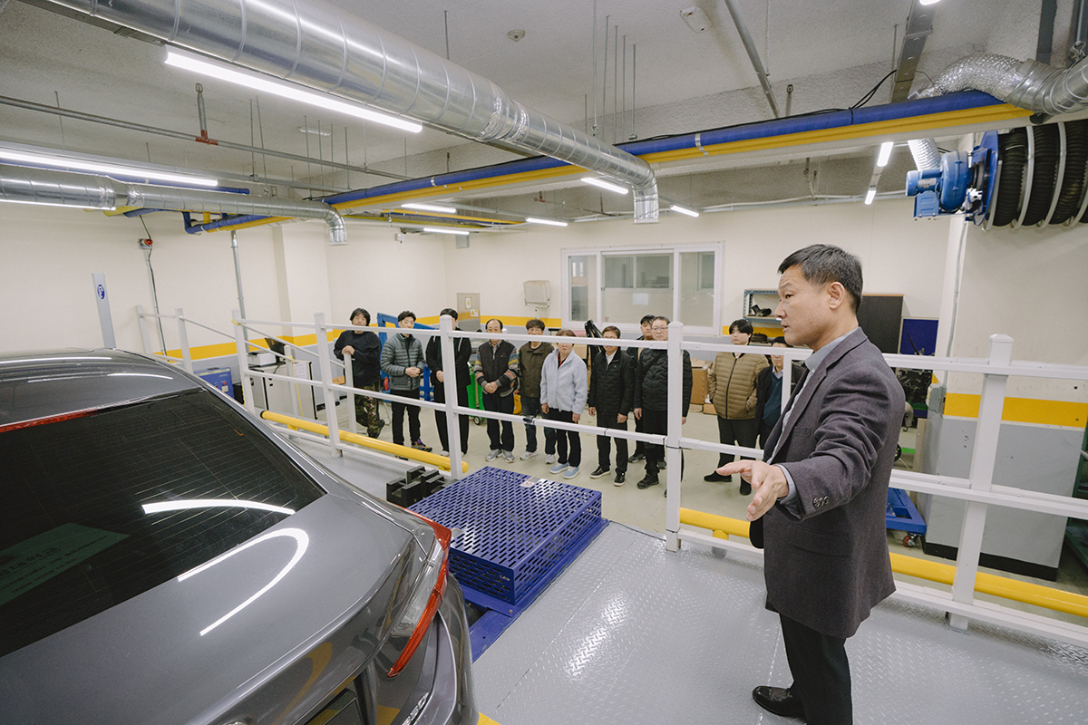 자동차 내부 부품들을 보며 설명하고 있는 교수님과 열심히 듣는 학생들