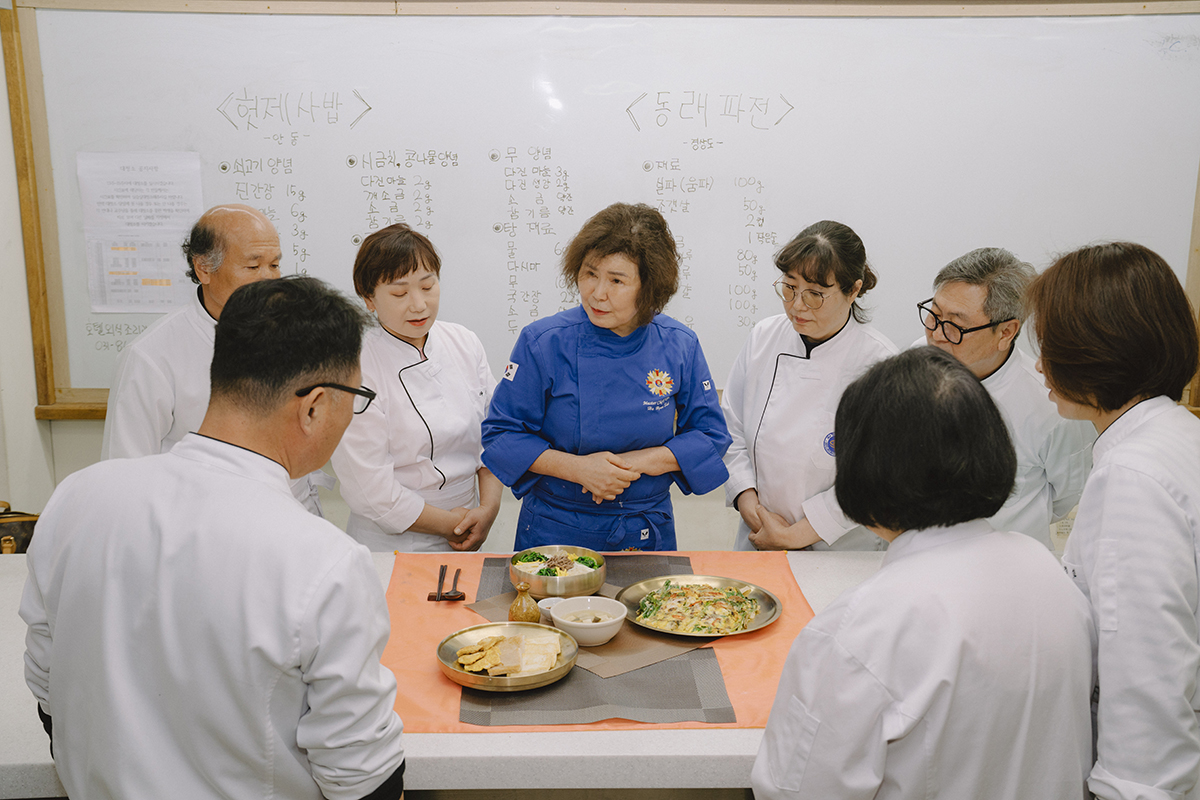 완성된 음식을 차려놓고 교수님의 설명을 듣는 학생들 사진